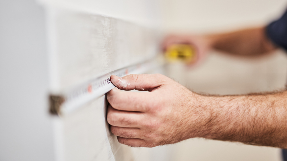 workman measuring a bathroom for tiles